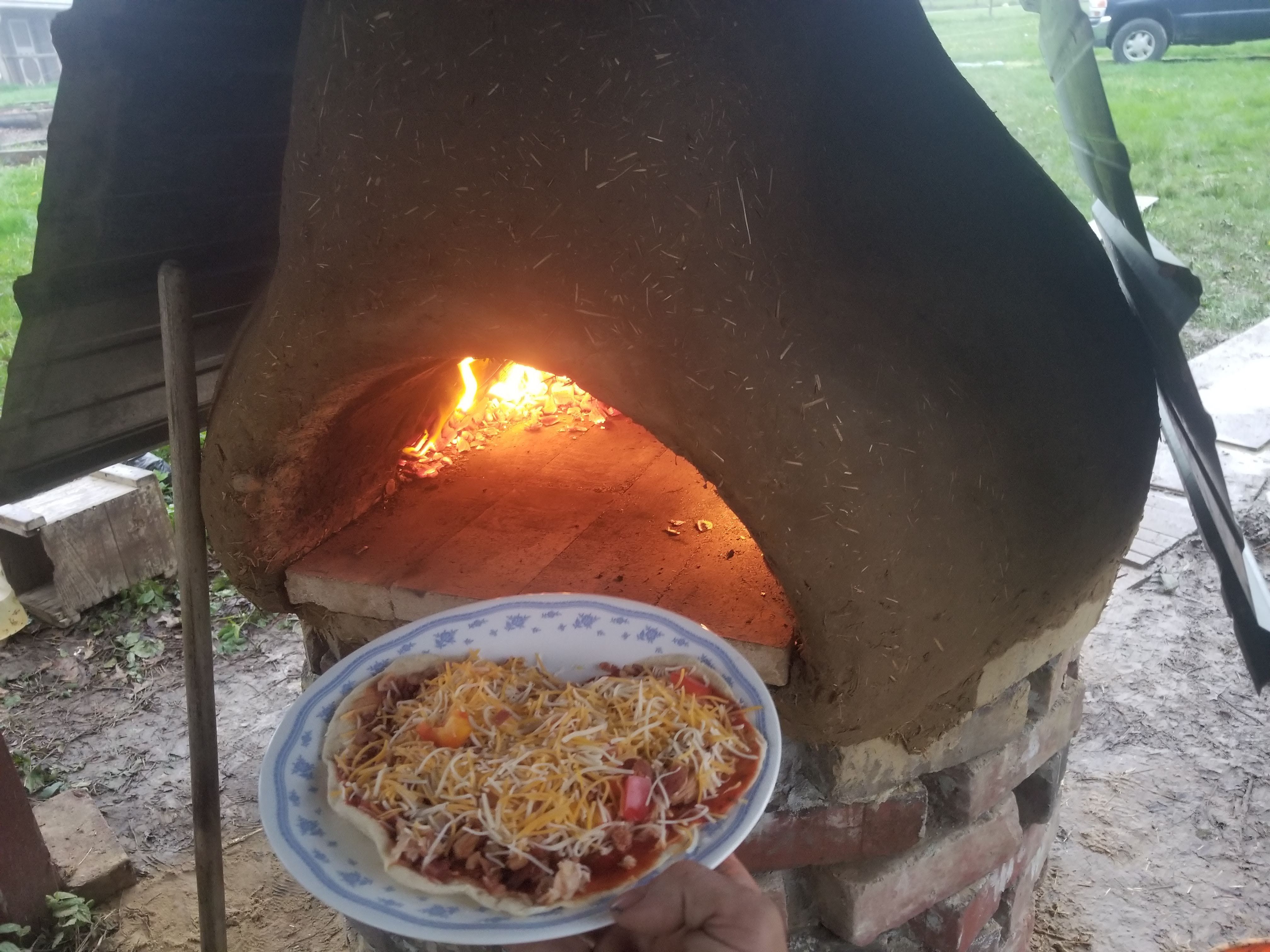 Throwing the pizza into the earthen cob oven