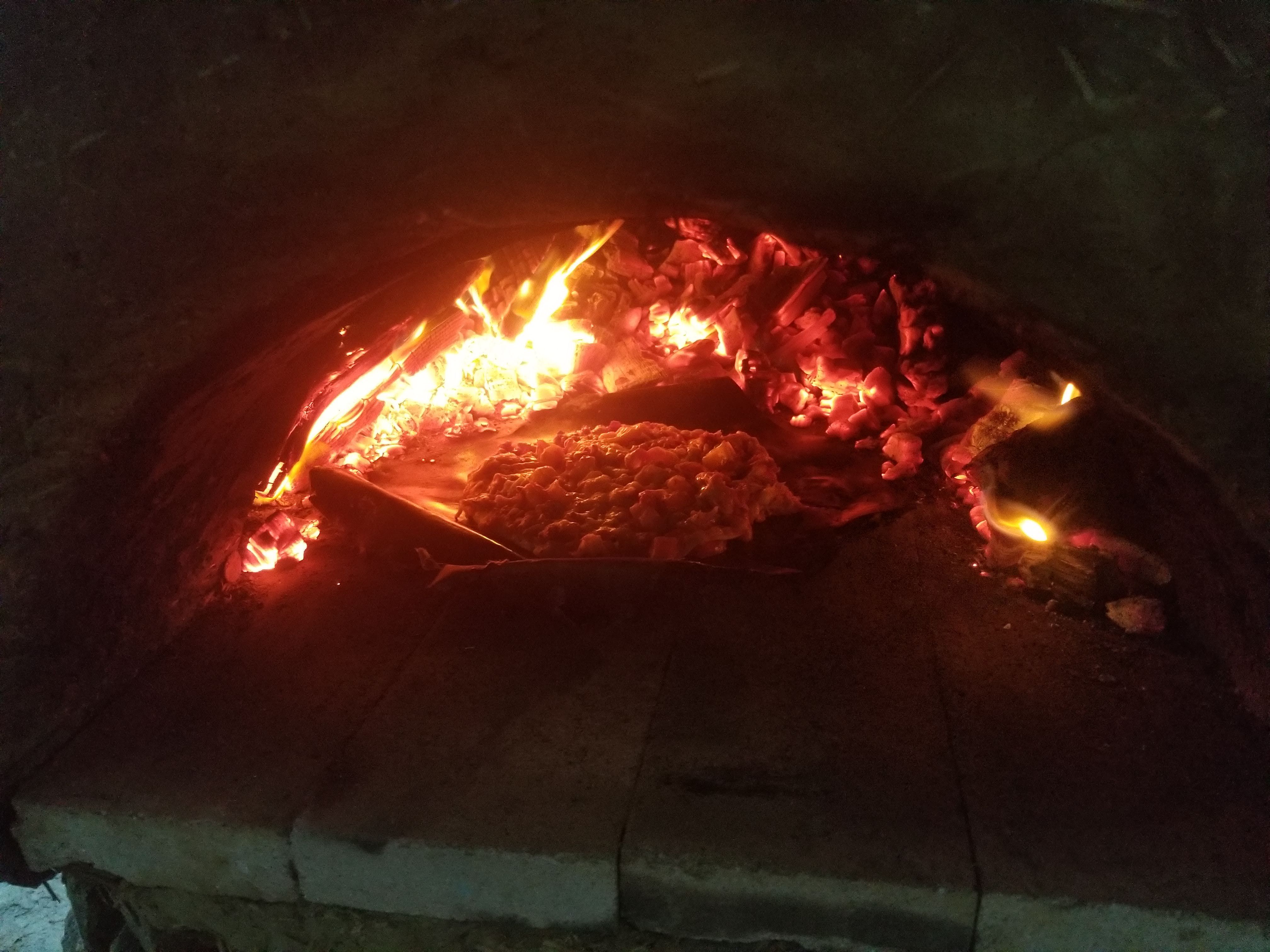 Baking the pizza in the earthen cob oven